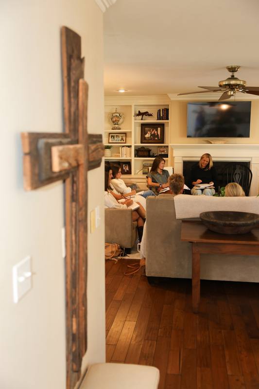 Cross on wall with women studying in background